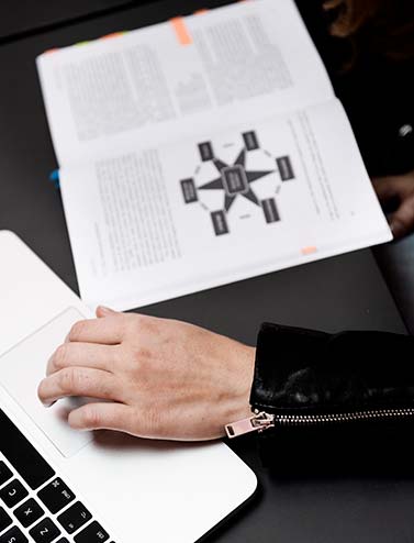 CBS student hand on a touch pad on a computer open book on the side